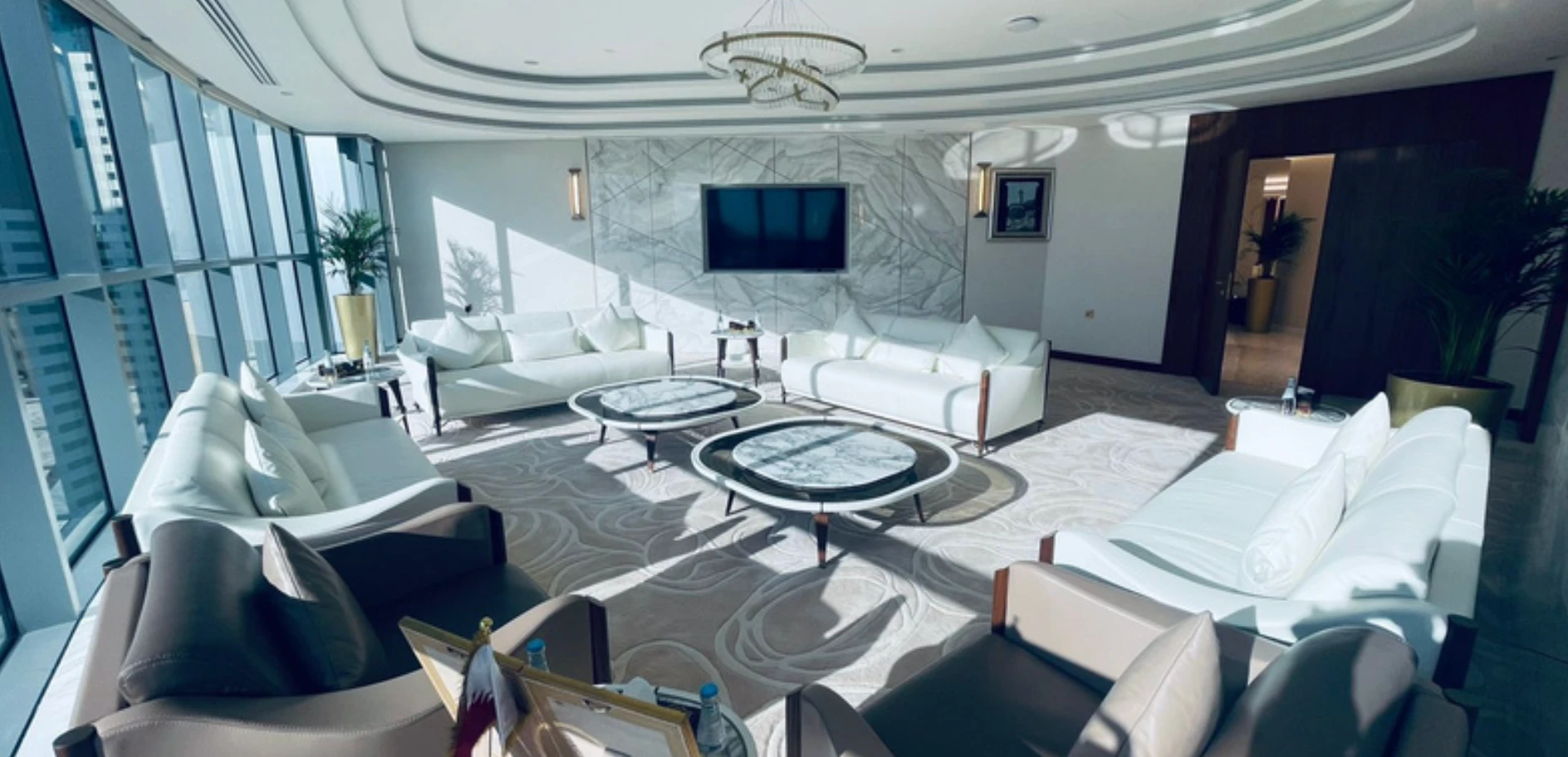 Formal lounge with white leather seating, marble tables, and floor-to-ceiling windows
