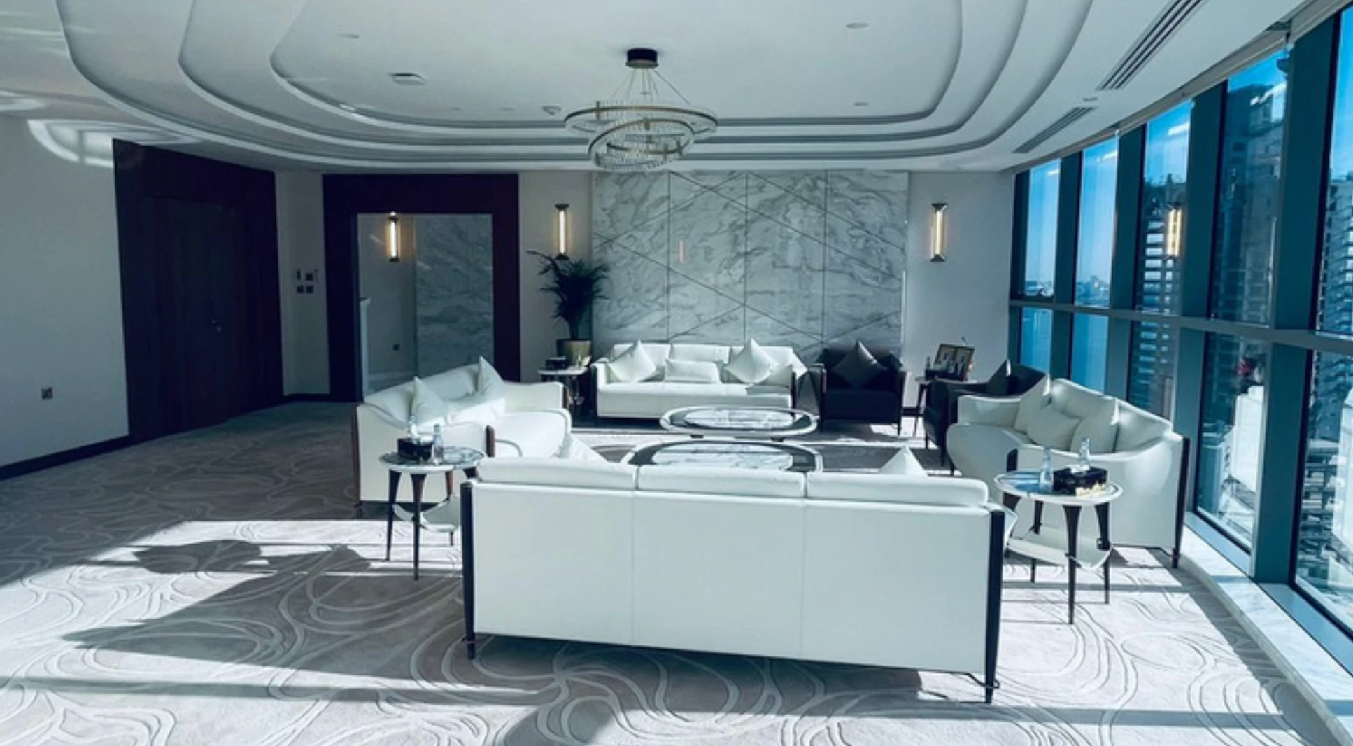Executive lounge with white and black leather seating, marble side tables, and a city view